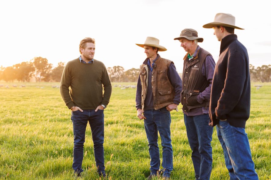 Curtis Stone talking to farmers in the field with sheep in the background