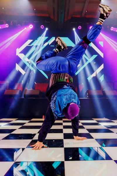 a hip hop dancer doing a hand stand on a black and white checkered dancefloor